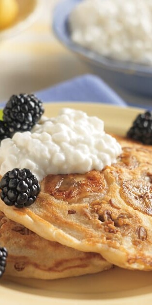 banana granola pancakes on plate with cottage cheese and blackberries on top