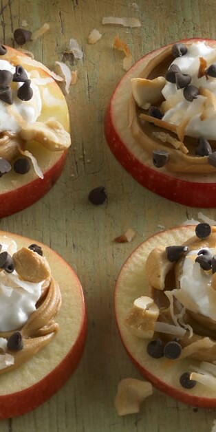 apple slices with peanut butter, cottage cheese, chocolate chips, and nuts on top