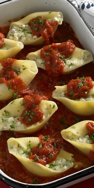 Three cheese stuffed shells in pan with red sauce